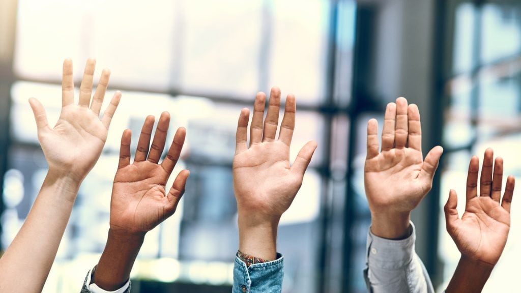 Diverse hands raised in a professional setting symbolising collaboration and inclusivity, representing GMS Accountants' commitment to personalised and accessible accounting services.