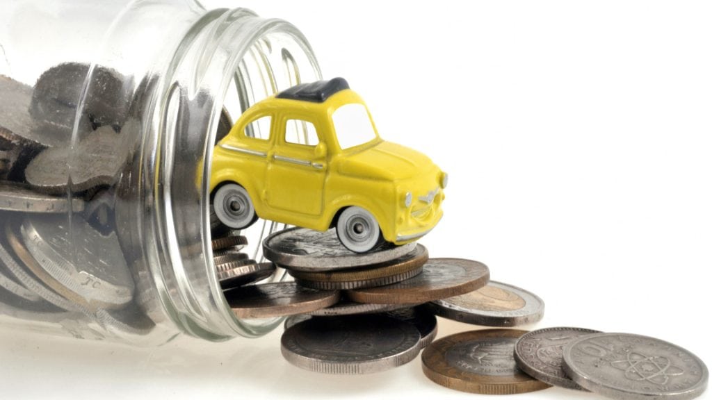 Bright yellow toy car atop a pile of mixed coins spilled from a glass jar, symbolising savings, financial growth, and affordable accounting services by GMS Accountants in the UK.