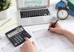 Professional accountant working on tax forms with calculator, laptop, and office supplies, providing expert tax preparation and financial services for small businesses and individuals in the UK.