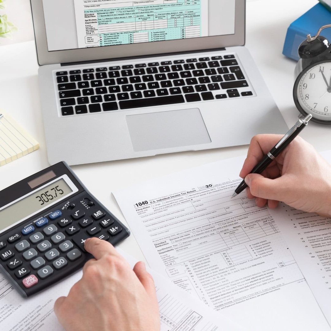 Professional accountant working on tax forms with calculator, laptop, and office supplies, providing expert tax preparation and financial services for small businesses and individuals in the UK.