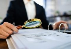 Magnifying glass inspecting financial documents at an accounting firm, representing thorough financial analysis and expert accounting services in the UK.