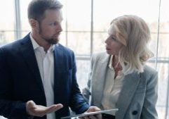 Professional accountants discussing finances using a tablet in a bright office environment.